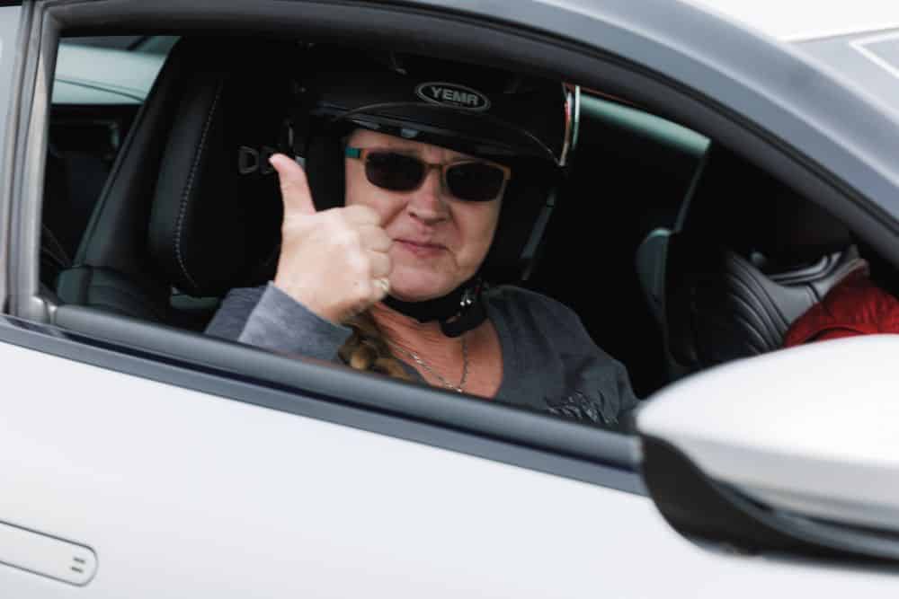 woman in car celebrates women in motorsport with thumbs up