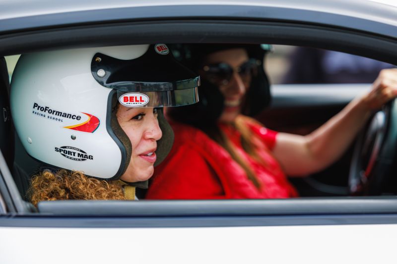Two women in race car with helmets