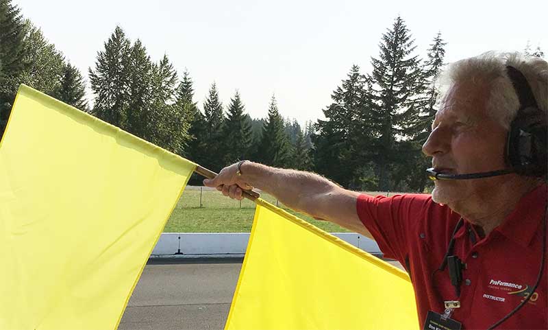 ProFormance Chief Instructor Don Kitch, Jr. holding yellow flag at race track.